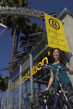 Image of a woman standing with her bike in front of the bikestation.