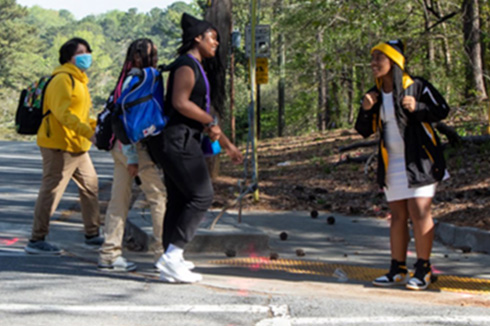 Six middle school students cross a street using a crosswalk during an educational pop-up demonstration.